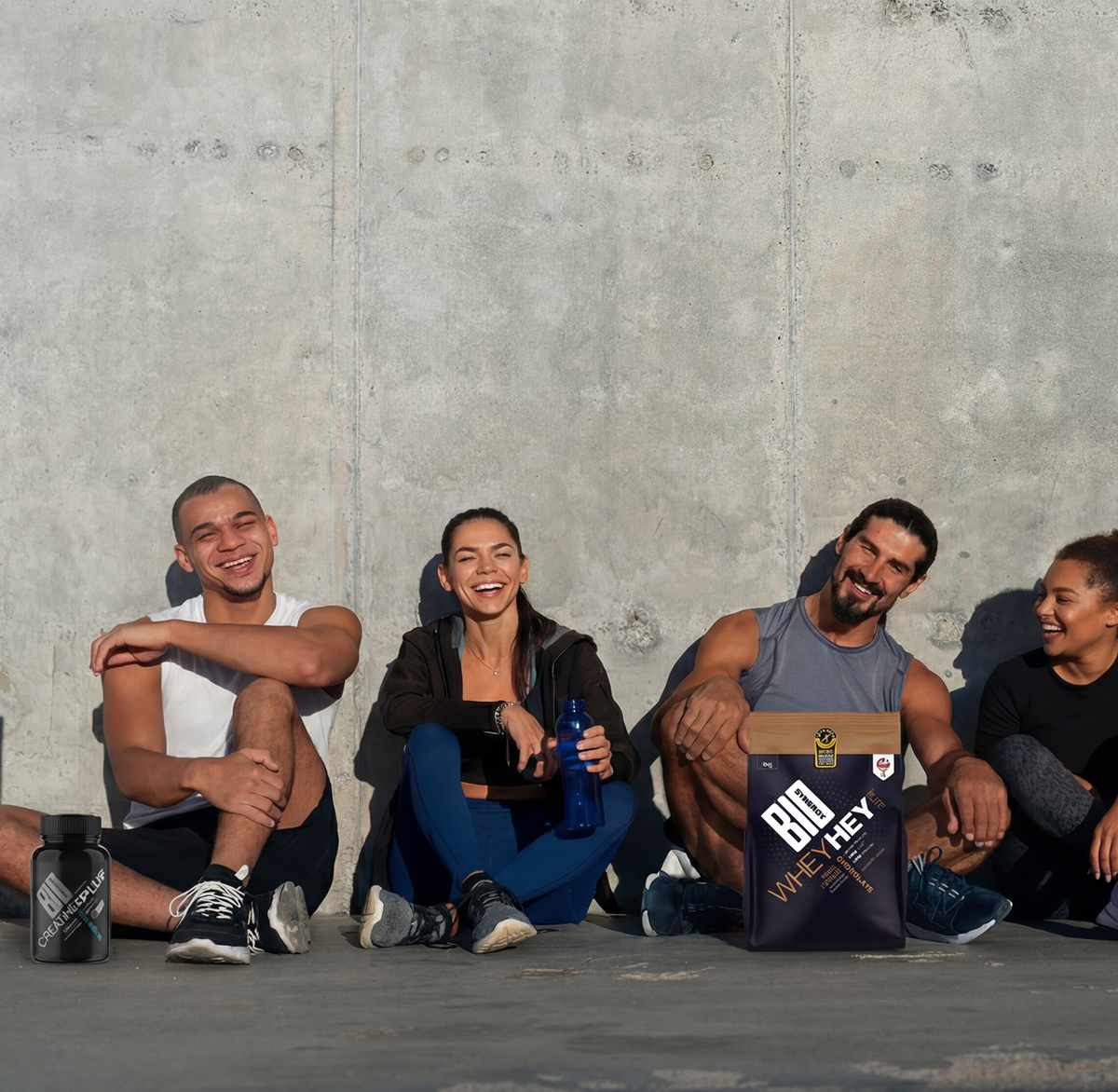 Group of diverse athletes sitting on floor with Bio-Synergy supplements